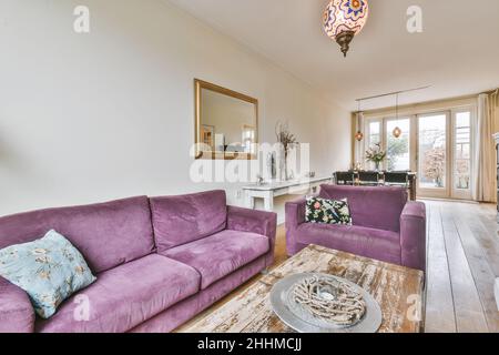 Charmantes Wohnzimmer mit purpurpurfarbenem Sofa aus Cord und Mosaik-Kronleuchter Stockfoto