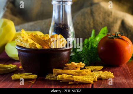 Gebratene Kartoffelchips auf dem Tisch und Zutaten Stockfoto