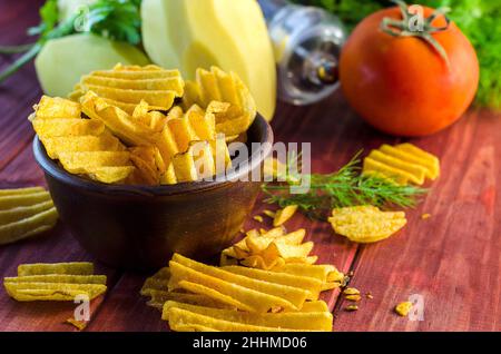 Gebratene Kartoffelchips auf dem Tisch und Zutaten Stockfoto