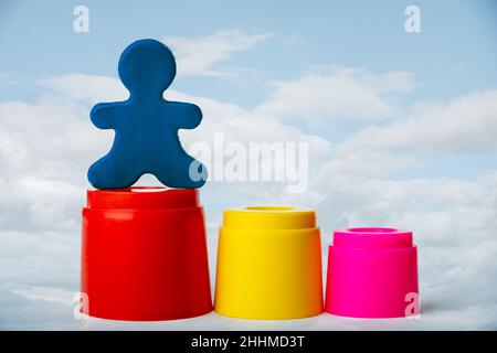 Ein Mann aus Plastilin, der auf dem höchsten Podium vor einem trendigen Hintergrund eines blauen Himmels mit Wolken steht. Führungskonzept. Stockfoto