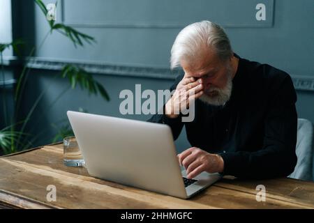 Besorgt reifer grauhaariger Großvater trauernd, erhielt schlechte Nachricht Benachrichtigung, allein zu Hause sitzen. Stockfoto