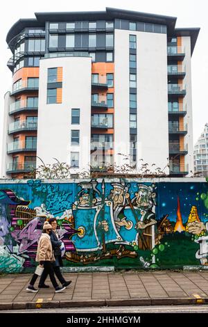 Kingston upon Thames, Großbritannien. 24th. Januar 2022. Zwei Personen gehen vor dem Apartmentgebäude des Älteren Hauses an mit Straßenkunst dekorierten Haufenauflagen vorbei. Stockfoto