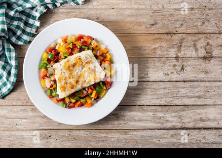 Gegrillter Kabeljau mit Gemüse in Teller auf Holztisch Stockfoto