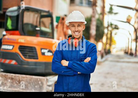 Junge kaukasische Arbeiter lächeln glücklich in Uniform in der Stadt. Stockfoto