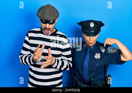 Ein Paar hispanischer Frauen und Männer mittleren Alters, die Diebe und Polizeiuniform trugen, zeigte mit Fingern, die Werbung zeigten, überraschte das Gesicht und war offen Stockfoto