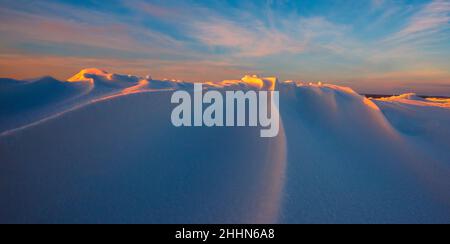 Schneeverwehungen im Abendlicht, lila Abendlicht im Winter mit viel Schnee, horizontales Landschaftsbild Stockfoto