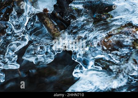 Fließendes Wasser aus einem Bach im Wald hat eine schöne Eisbildung gebildet Stockfoto