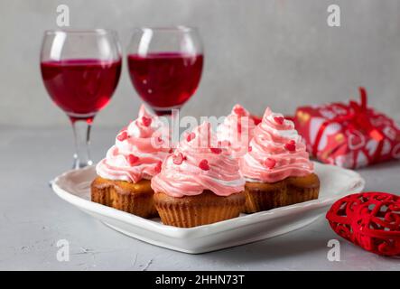 Hausgemachte Cupcakes mit Creme- und herzförmigen Prise zum Valentinstag auf hellem Hintergrund Stockfoto