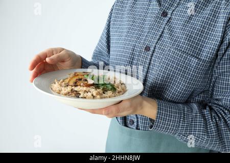 Frau in Schürze hält Teller mit Risotto mit Pilzen Stockfoto