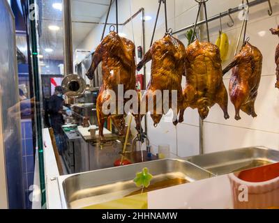 ATHEN, GRIECHENLAND - 15. JANUAR 2022: Nahaufnahme einer leckeren knusprig gerösteten Peking-Ente, die in einem Fenster in der chinesischen Restaurantküche hängt. Gekochte Speisen Stockfoto