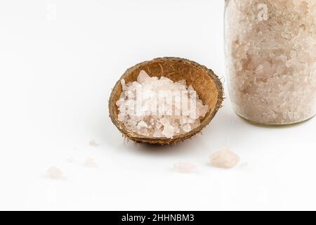 Meersalz in einem Glas und ein paar Badesalz in Kokosnuss-Schale auf weißem Hintergrund Stockfoto