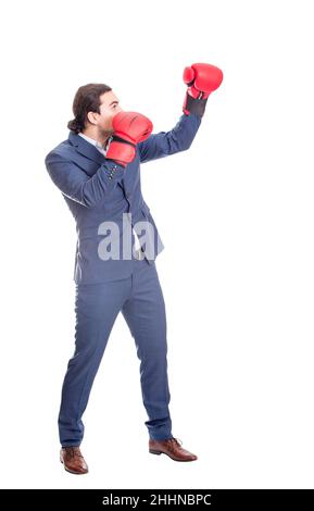 Ganzlänge Geschäftsmann mit roten Boxhandschuhen, Stanzen mit der Hand, Kampfposition. Seitenansicht Porträt eines entschlossenen Geschäftsreisenden, der mit fis tritt Stockfoto