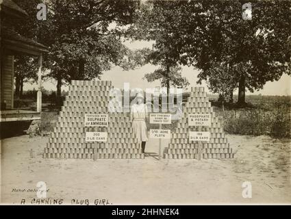 Frau Eron Dooley von Bishop, nahe Athen, Georgia, USA, steht zwischen zwei Stapeln Tomatendosen - frühes Canning Club-Foto - Anfang des 20. Jahrhunderts Stockfoto