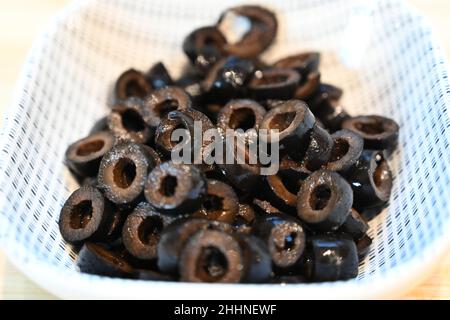 Schwarze Oliven in Scheiben geschnitten, Zutaten zum Kochen, Zubereitung von Speisen Stockfoto