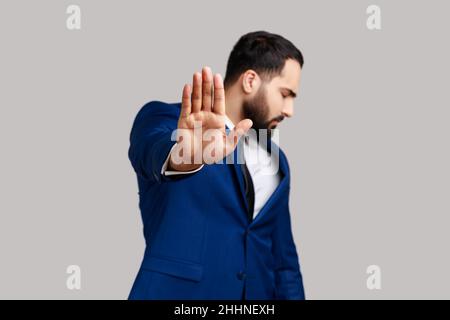 Bärtiger Mann macht eine Stop-Geste, zeigt Handfläche und dreht den Kopf beiseite, Konfliktverbot warnt vor Gefahr, hört auf zu Mobbing. Innenaufnahme des Studios isoliert auf grauem Hintergrund. Stockfoto