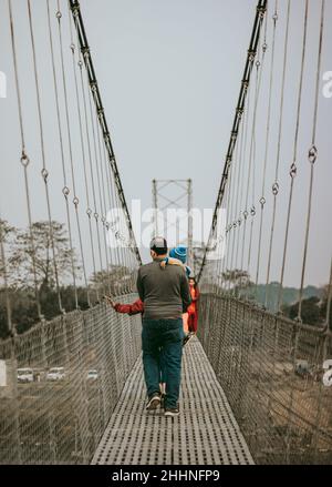 Mann in grüner Jacke und schwarzer Hose, der auf der Brücke läuft Stockfoto