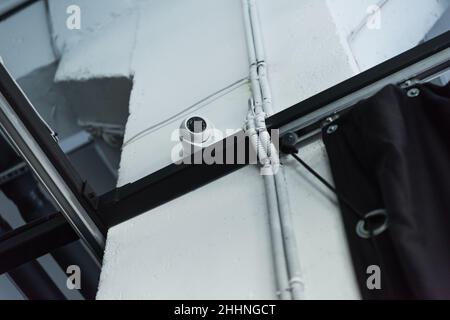 Low-Angle-Ansicht der Überwachungskamera auf Metallkonstruktion in der Nähe einer weißen Wand Stockfoto