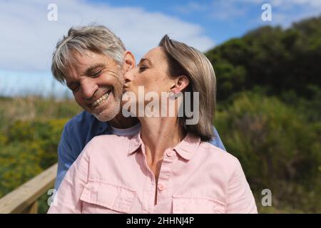 Kaukasische reife Frau küsst glücklichen Mann mit geschlossenen Augen. Zweisamkeit, Wochenende, Lifestyle und Liebeskonzept. Stockfoto