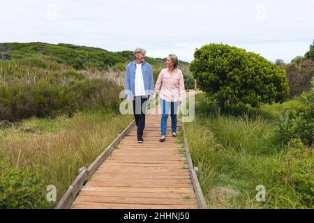 Ganze Länge des kaukasischen Paares lächelt beim Spaziergang auf der Promenade während des Wochenendes. Zweisamkeit, Wochenende und Naturkonzept. Stockfoto