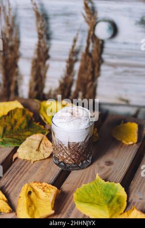 Vertikale Aufnahme eines Glases heißen Kakaos mit Schlagsahne und Zimt auf dem Tisch Stockfoto