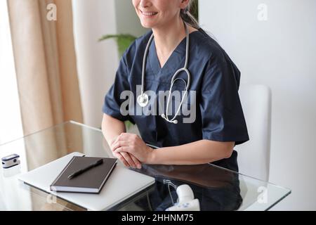 Kinderärztin am Tisch sitzend, lächelnd, Porträt Stockfoto