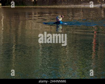 Frau, die im Januar in Cornwall, Großbritannien, im Bude Sea Pool kaltes Wasser schwimmt Stockfoto