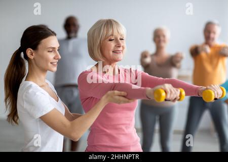 Eine junge Trainerin hilft älteren Frauen beim Training Stockfoto