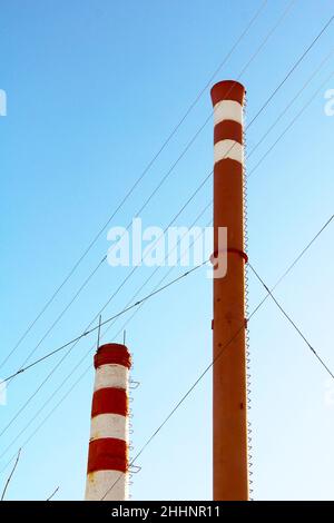 Rauch von einem roten und weißen Kamin auf blauem Himmel Hintergrund. Raumheizung in einer städtischen Umgebung. Leerer Platz für Text und Design. Stockfoto