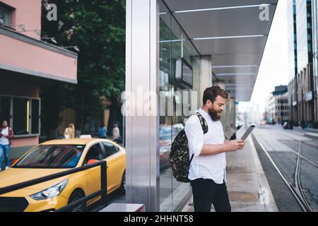 Ernsthafter Mann mit Tablet an der Straßenbahnhaltestelle Stockfoto