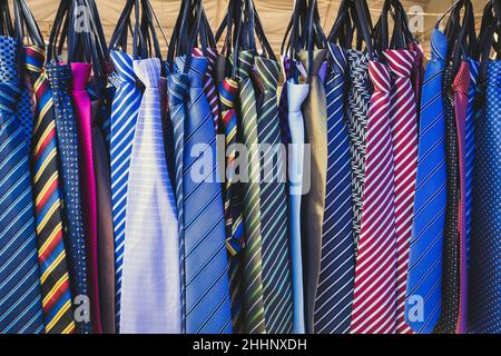 Große Auswahl an bunten Krawatten hängen in den Verkauf auf dem Straßenmarkt. Viele verschiedene Muster bunte Krawatten hängen auf Kleiderständer. Farbe Stockfoto