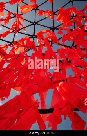 Rote Stoffstreifen hängen auf einem Netz gegen den blauen Himmel Stockfoto