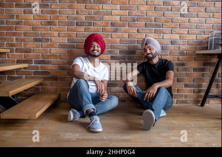 Zwei junge Männer sitzen zu Hause auf dem Boden und sehen entspannt aus Stockfoto