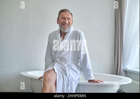 Glücklicher reifer Mann beim Träumen im Badezimmer Stockfoto