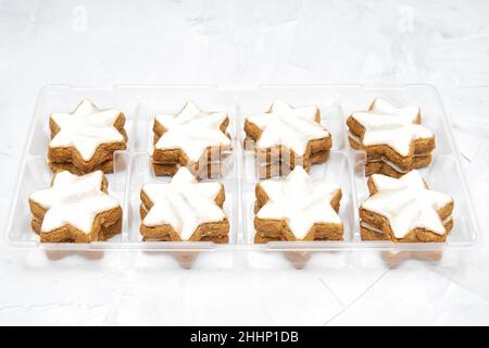 Deutsche Zimt-Stern-Kekse in einem transparenten Ladentisch auf einem betonierten Tischhintergrund. Weihnachtszeit Süßigkeiten. Stockfoto
