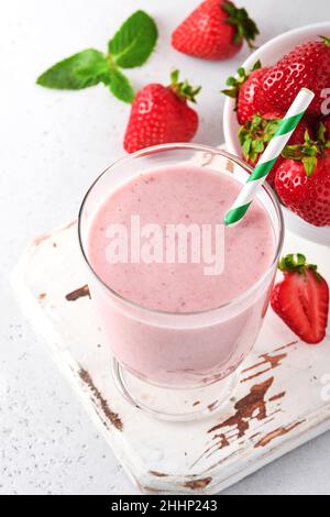 Obst-Smoothie. Erdbeer-Smoothie oder Milchshake mit Beeren und Minze in hohem Glas auf hellgrauem Hintergrund. Sommergetränk Shake, Milchshake und Refrain Stockfoto