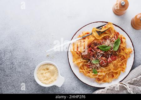 Tagliatelle Pasta mit Fleischbällchen in Tomatensauce und Thymian in Sauce auf hellgrauem Schiefer, Stein oder Beton Hintergrund. Traditionelles italienisches Gericht und Cu Stockfoto
