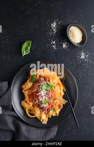 Tagliatelle Pasta mit Fleischbällchen in Tomatensauce, Basilikum und Parmesankäse auf schwarzem Stein oder Beton. Traditionelle italienische Gerichte und Küche Stockfoto