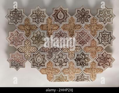 Tafel bestehend aus Fliesen in Form von achtspitzigen Sternen und Kreuzen 1260–70 Tafeln bestehend aus acht spitzen Sternen und Kreuze häufig geschmückte Wände religiöser Bauwerke im Iran während der Ilkhanid-Zeit. Die aufwändigen Muster auf diesen Fliesen sind in einem bräunlich-roten Glanz auf weißer, opaker Glasur lackiert. In diesem Beispiel wurden die kreuzförmigen Fliesen mit einem schlichten Design im 20. Jahrhundert gebaut, um die fehlenden zu ersetzen, als die Platte montiert wurde. In der Mitte dieser Fliesen sehen wir abstrakte vegetale Muster, ein Motiv, das mit Keramiken und Fliesen aus dem Iran übereinstimmt Stockfoto