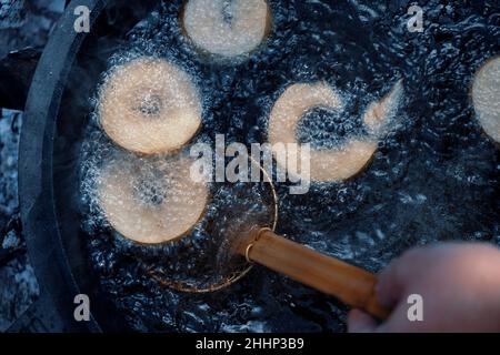 Hausgemachte Donuts Braten in Gusseisen Pfanne im Freien auf dem Campingplatz. Stockfoto