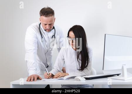 Die junge Ärztin berät sich mit dem Chefarzt. Zwei Ärzte im Büro Stockfoto