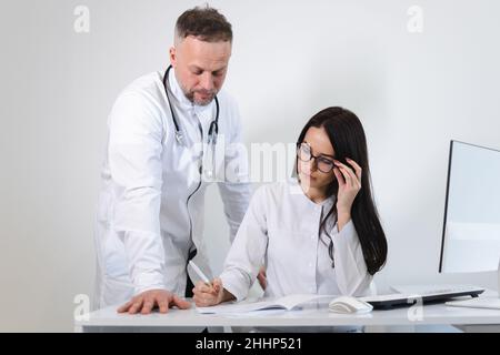Die junge Ärztin berät sich mit dem Chefarzt. Zwei Ärzte im Büro Stockfoto