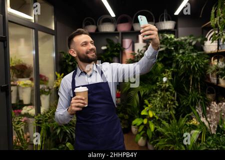 Junger männlicher Unternehmer, der Selfie im Blumenladen nimmt Stockfoto