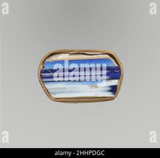 Glasmosaik-Inlay-Fragment Ende 1st. Jahrhundert v. Chr.–Anfang 1st. Jahrhundert n. Chr. römisch Durchscheinend Kobaltblau und opakes Weiß.dünner, flacher Streifen oder Paneel, mit geraden Seiten und abgewinkelten Enden; unebene Oberfläche auf der Unterseite.Streifen von streifendem Weiß auf der Oberseite; Ein breites, mittiges Band aus Weiß auf blauem Grund auf der Unterseite.einige Kanten sind abgesplittert und uneben; polierte Oberfläche; Lochfraß von Oberflächenblasen auf der Oberseite; stumpfende und cremige Verwitterung auf der Unterseite und an den Kanten.wahrscheinlich als Dekoration in Wand- oder Deckenverzierungen oder als Einlage für Möbel verwendet. Glasmosaik-Inlay-Fragment. Roman. Spät Stockfoto