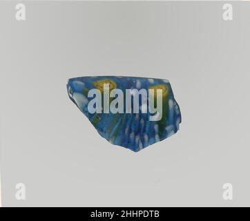 Glasmosaik geripptes Schalenfragment Ende des 1st. Jahrhunderts v. Chr.–Anfang des 1st. Jahrhunderts n. Chr. römisches Randfragment.Durchscheinendes Kobaltblau, opakes Weiß und Gelb.ausgespielter, abgerundeter Rand; konkaver, kurviger Hals, fast gerade side.Composite Mosaikmuster aus polygonalen Abschnitten von zwei oder mehr Stöcken: Eine auf blauem Grund mit einem Kreis aus weißen Stäben um eine zentrale, enge gelbe Spirale; eine zweite auf blauem Grund mit einem zentralen weißen Stab, der von einem Kreis aus gelben Punkten umgeben ist; Außen, oben auf einer einzelnen vertikalen Rippe, oben im Quadrat, und unregelmäßige horizontale Werkzeugskizzuren um den Hals.Innenpolishe Stockfoto