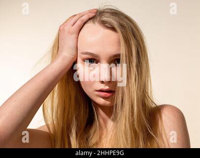 Junge Frau mit blondem Haar isoliert auf beigefarbenem Porträt Stockfoto