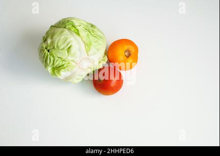 Weißkohlkopf und zwei rote Tomaten isoliert auf weißem Hintergrund ein ganzer Kopf mit Kopierraum. Stockfoto