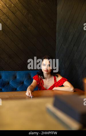 Seriöse europäische junge dunkelhaarige Frau mit weißer Haut in dunklem Holzzimmer Stockfoto