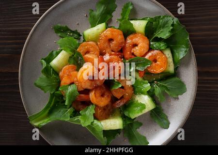 Frischer Salat mit gegrillten Garnelen, Gurken und Rucola, wunderschön auf einem Teller serviert, Draufsicht, flach liegend. Stockfoto