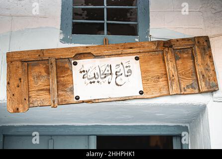 Der Name eines traditionellen Ladens in Tunis, geschrieben auf einer alten Holztür in arabischer Kalligraphie Stockfoto