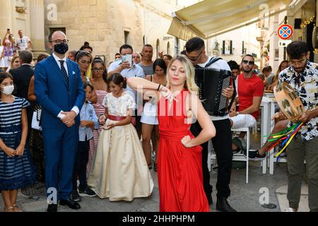 LECCE, ITALIEN - 19. AUGUST 2021, Frau in rotem Kleid tanzen barfuß apulischen Volkstanz nennen pizzica oder taranta auf der Sommerstraße von Lecce und peop Stockfoto